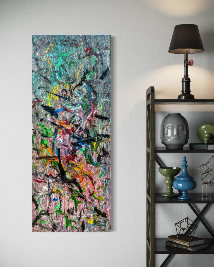 Tall vertical abstract painting with multicolored splatters on a light wall beside a black metal shelf with decorative objects and a lamp.