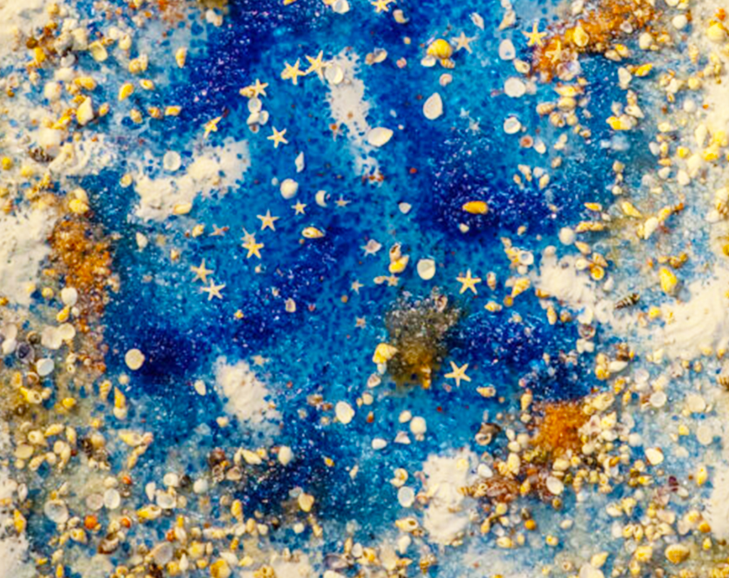 Blue abstract beach artwork with small starfish shapes and scattered shell pieces/confetti across a textured surface.