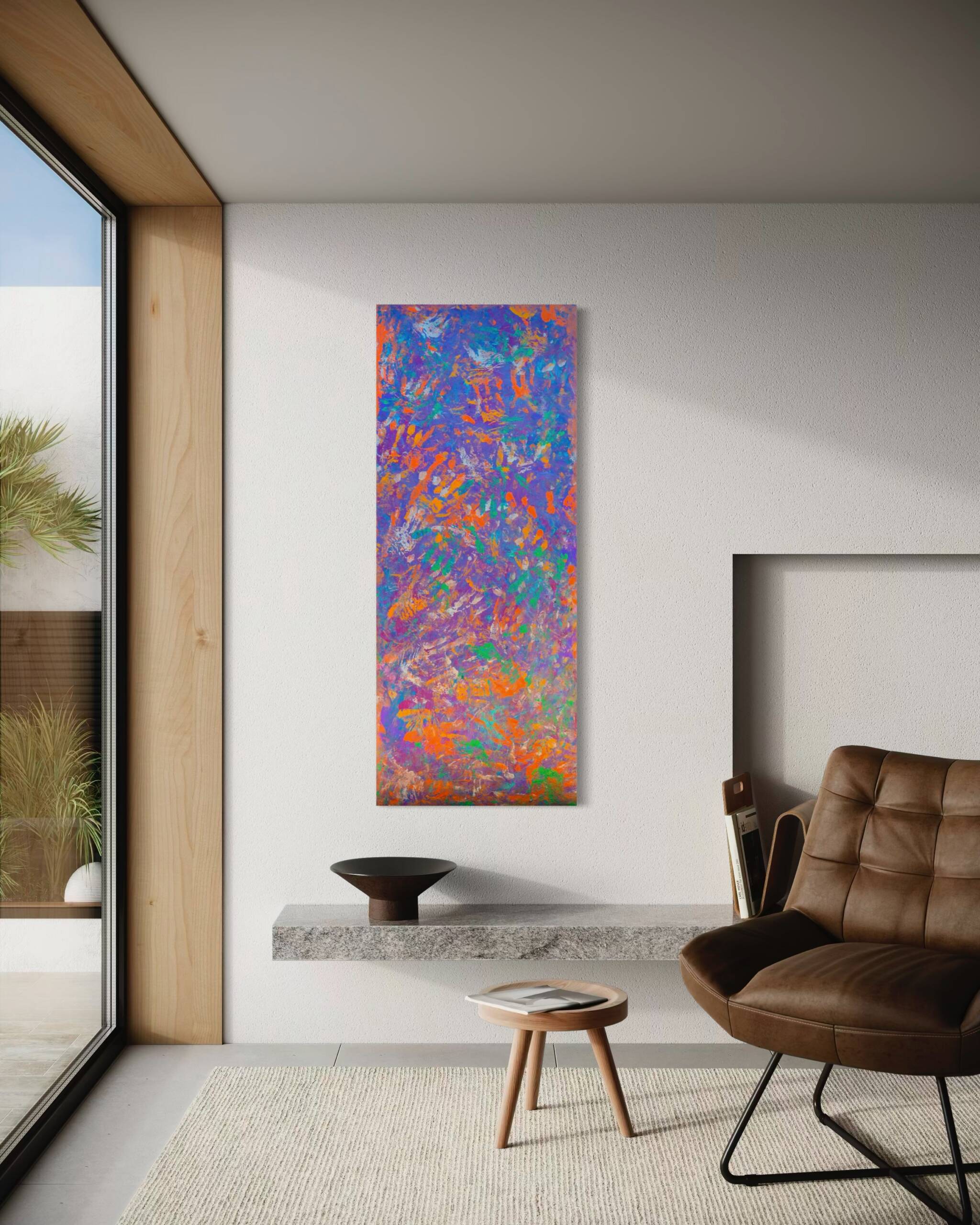 Vertical abstract colorful painting on a light wall in a modern living room with a glass wall to the left and a brown leather chair nearby.