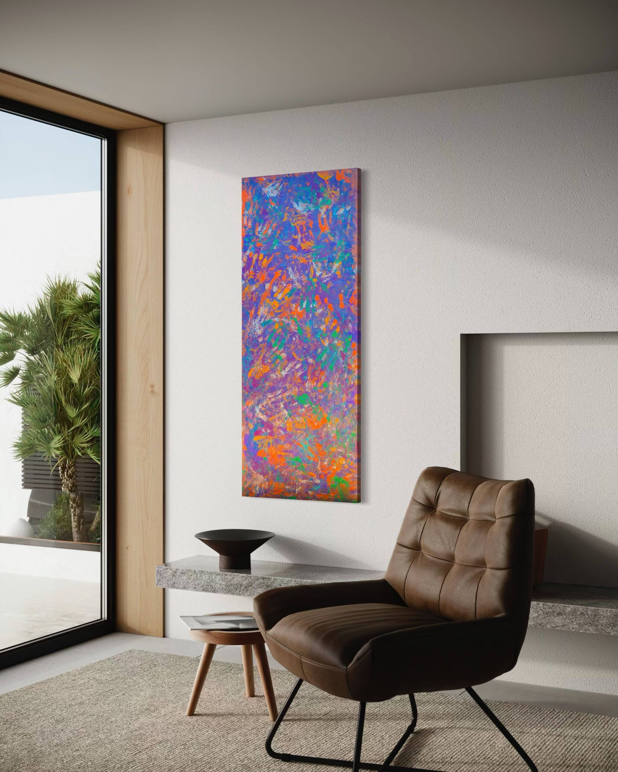 Vertical colorful abstract painting on a beige wall beside a brown leather lounge chair in a modern living room.